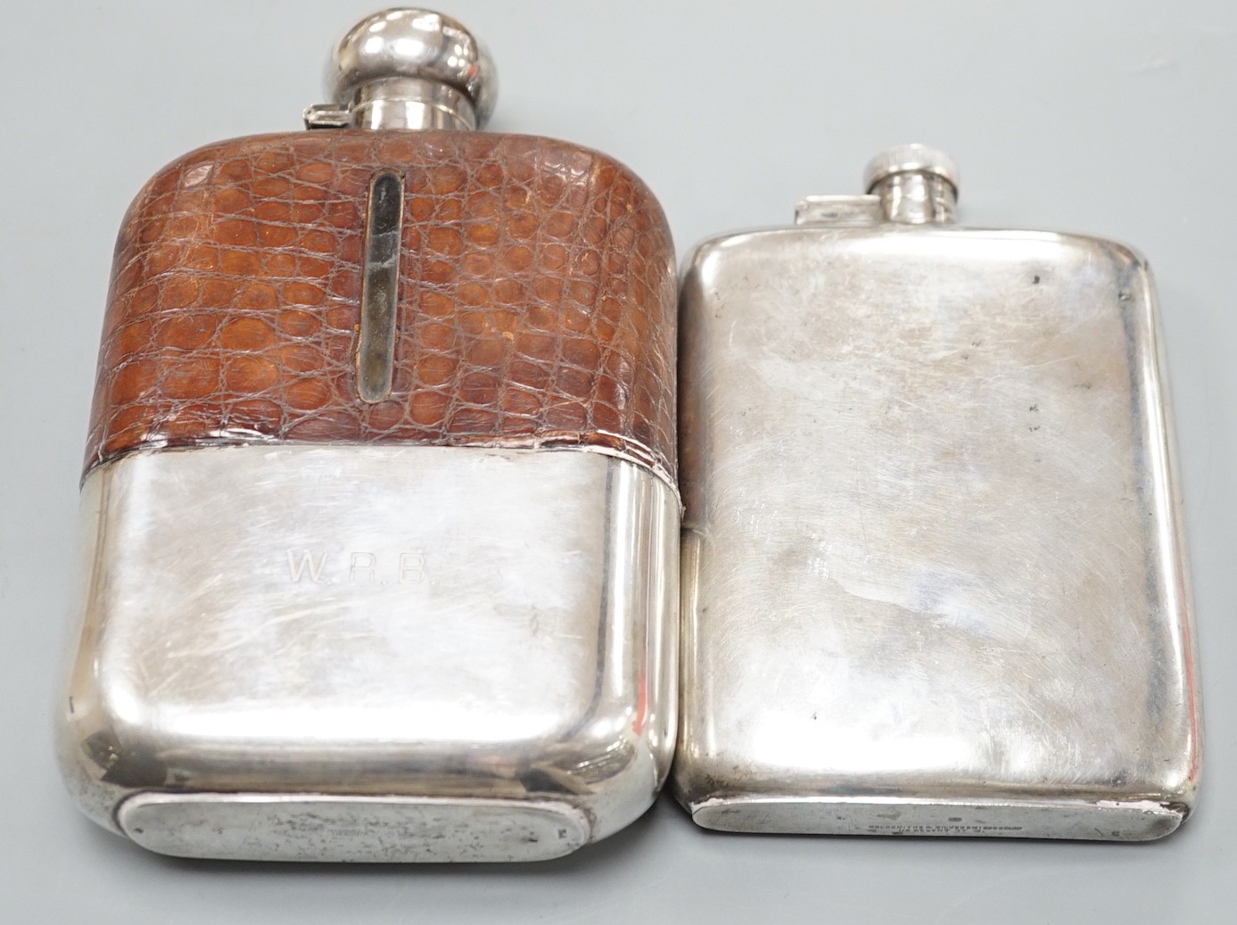 A George VI silver hip flask, Goldsmiths & Silversmiths Co Ltd, London, 1938, 15.4cm, 7.6oz and a large George V silver and crocodile skin mounted glass hip flask, James Dixon & Sons, Sheffield, 1920, 19cm.